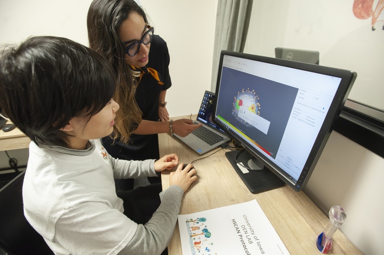 Adult working with child at computer monitor