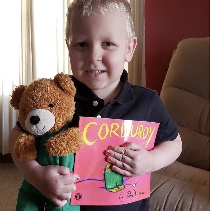 Child holding a book and stuffed bear